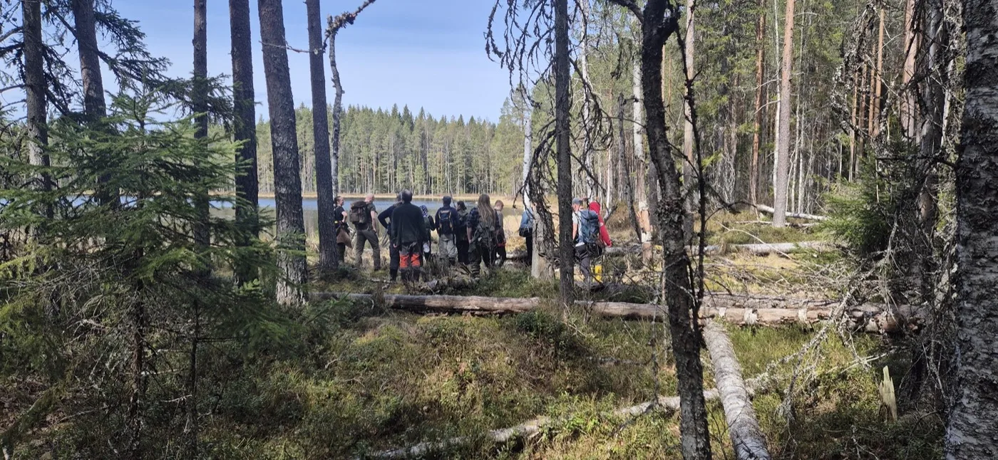 Ennallistajien retkiporukka Seitsemisen kansallispuistossa lammen rannalla